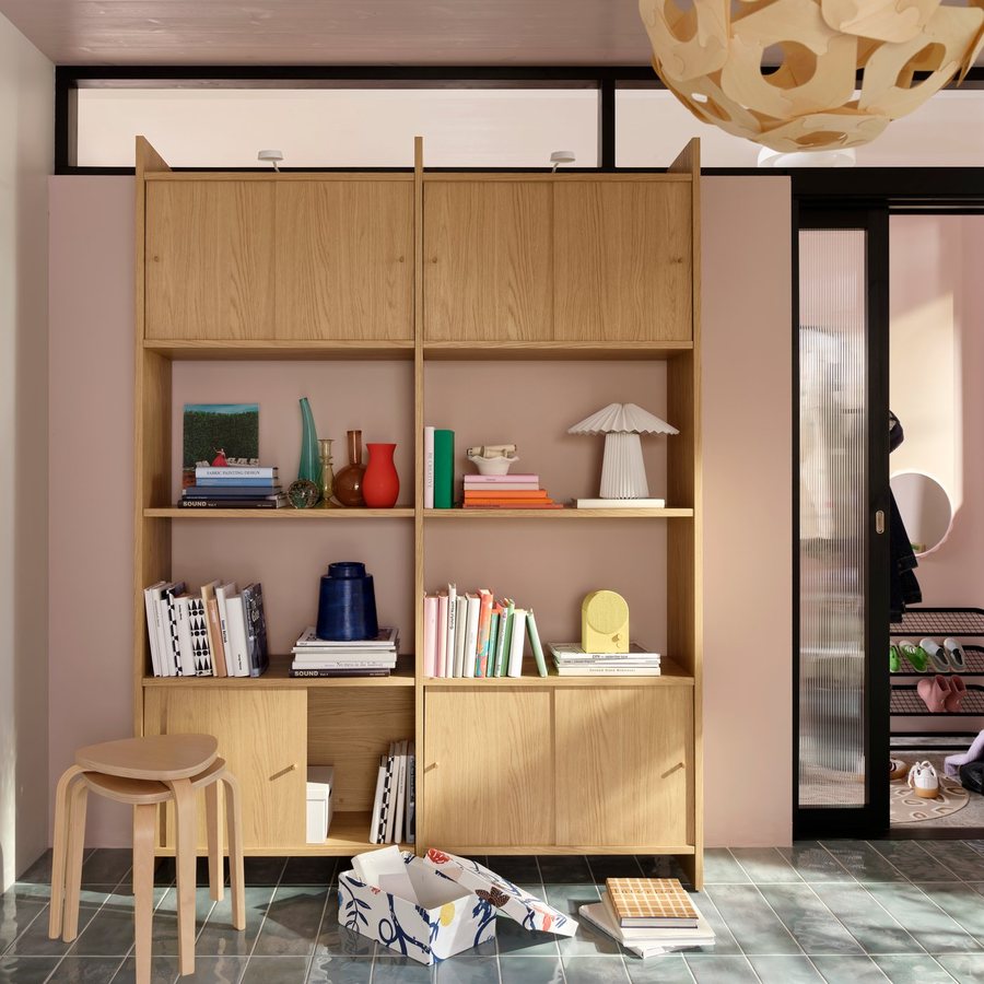 A floor-to-ceiling oak storage unit with closed cupboards above and below open shelves