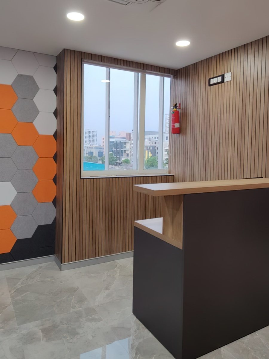 A bank branch reception Woodware furnished — a wood-fronted counter against a hexagon-panelled wall at ICICI Bank, Baner